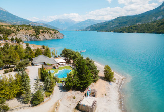 Aerial view of Camping La Presqu’île holiday park by a blue lake and mountains in Provence-Alpes-Côte d’Azur, France.