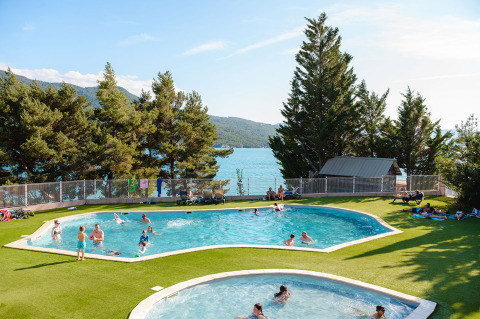 Holiday park with swimming pools and lake view at Camping La Presqu’île in Provence-Alpes-Côte d’Azur, France.