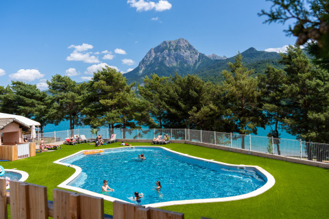 Außenpool mit Blick auf einen See und Berge im Ferienpark Camping La Presqu’île, Provence-Alpes-Côte d’Azur.