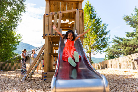 Una bambina felice scende dallo scivolo al parco giochi del Camping La Presqu’île in Provenza, Francia.