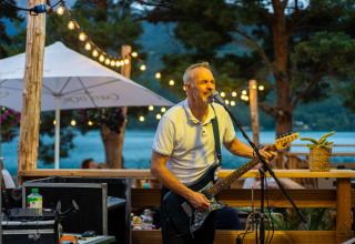 Uomo suona la chitarra elettrica e canta su una terrazza all’aperto al Camping La Presqu’île, Provenza-Alpi-Costa Azzurra.