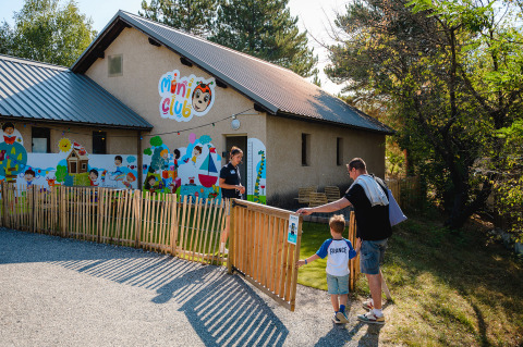 Padre e hijo entran al mini club en Camping La Presqu’île, parque vacacional en Provence-Alpes-Côte d’Azur, Francia.