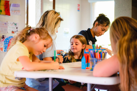 Bambini e adulti fanno attività artistiche a un tavolo al Camping La Presqu’île, Provence-Alpes-Côte d’Azur.