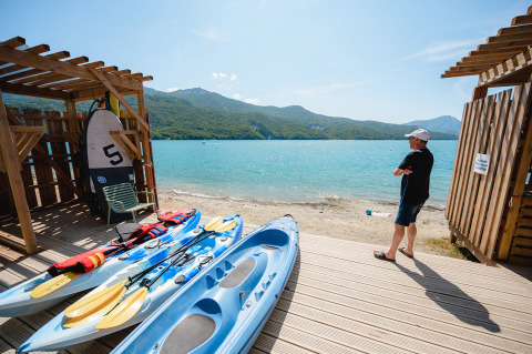Uomo in riva al lago con kayak e pagaie al Camping La Presqu’île, Provenza-Alpi-Costa Azzurra, Francia.