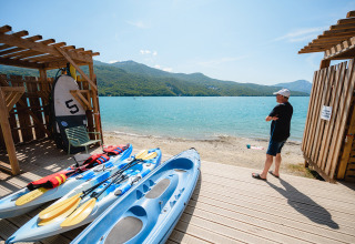 Man aan het meer met kajaks en peddels bij Camping La Presqu’île, Provence-Alpes-Côte d’Azur, Frankrijk.