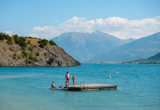 Personnes sur un ponton flottant au Camping La Presqu’île en Provence-Alpes-Côte d’Azur, France, devant les montagnes.