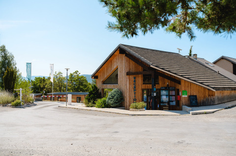 Receptiegebouw van Camping La Presqu’île, een vakantiepark in Provence-Alpes-Côte d’Azur, Frankrijk, omringd door bomen.