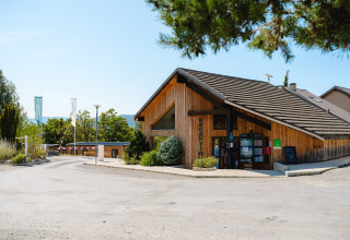 Edificio della reception al Camping La Presqu’île, villaggio vacanze in Provenza-Alpi-Costa Azzurra, Francia, circondato dal verde.