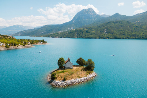 Piccola isola con una casa circondata da acqua blu al Camping La Presqu’île, Provence-Alpes-Côte d’Azur, Francia.