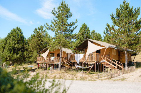 Safari tents on wooden decks at Camping La Presqu’île in Provence-Alpes-Côte d’Azur, surrounded by pines.