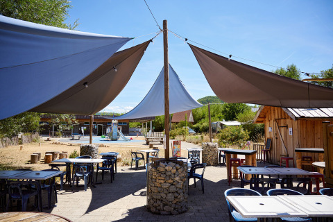 Außenbereich eines Cafés mit Sonnensegeln und Tischen im Camping La Roche d’Ully, Bourgogne-Franche-Comté, Frankreich.
