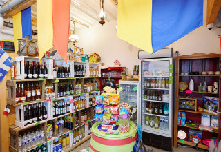 Indvendigt billede af butik i Camping La Roche d’Ully med farverige flag, legetøj og hylder med varer.