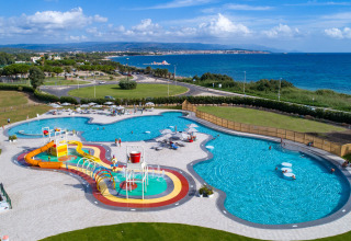 Aerial view of Camping Laguna Blu holiday park in Sardinia with pool, water slides and a sea background.