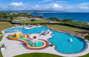 Aerial view of Camping Laguna Blu holiday park in Sardinia with pool, water slides and a sea background.