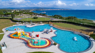 Vista aerea di Camping Laguna Blu in Sardegna con piscina, scivoli d’acqua e panorama sul mare.
