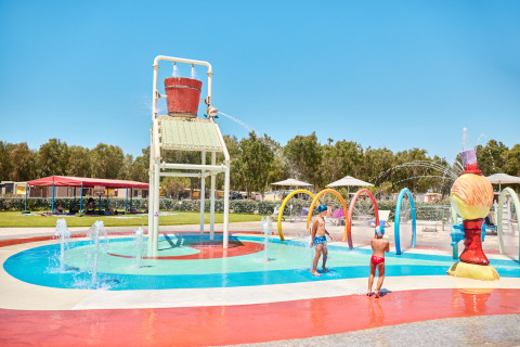 Niños juegan bajo un gran cubo de agua en la zona acuática del Camping Laguna Blu en Cerdeña, Italia.