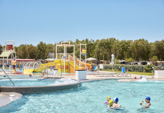 Børn leger i en vandpark på Camping Laguna Blu i Sardinien, Italien, med rutsjebaner og pool.