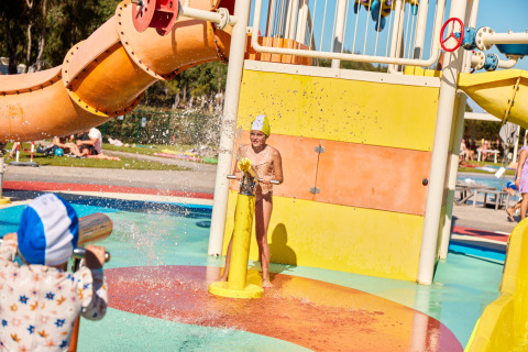 Bambini che giocano con i cannoni d'acqua al parco acquatico di Camping Laguna Blu, in Sardegna, Italia.