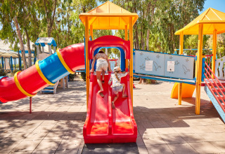 Kinder spielen auf einem bunten Spielplatz mit Rutschen im Camping Laguna Blu in Sardinien, Italien.