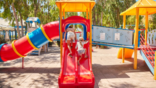 Children playing on a colorful playground with slides at Camping Laguna Blu holiday park in Sardinia, Italy.