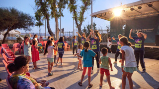 Children and adults enjoying evening entertainment with group dancing at Camping Laguna Blu holiday park, Sardinia.