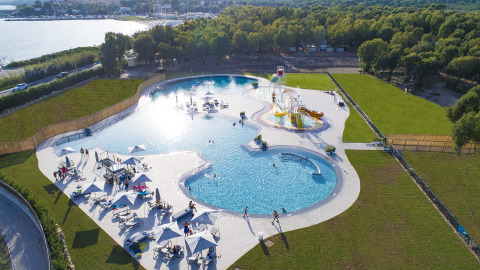 Vista aérea de complejo de piscinas con toboganes y tumbonas en Camping Laguna Blu, Cerdeña, Italia.