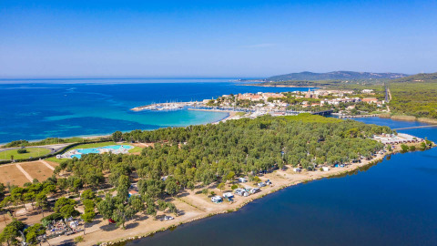 Vista aérea de Camping Laguna Blu, parque vacacional en Cerdeña, Italia, con mar y frondosos árboles.