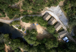 Aerial view of Camping Le Canigou in Occitanie, France, featuring tents, trees, and a nearby pond.