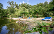 Afslappende søstrand med blå liggestole og frodige træer på Camping Le Canigou, Occitanie, Frankrig.