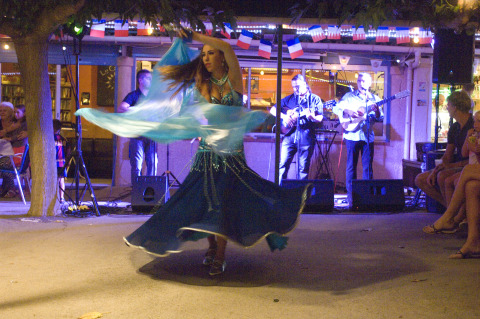 Una bailarina de danza del vientre actúa ante músicos en vivo y público en Camping Le Canigou, Occitania, Francia.