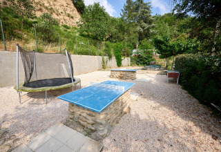 Udendørs lege- og spilområde på Camping Le Canigou med bordtennisbord, trampolin og bordfodbold.