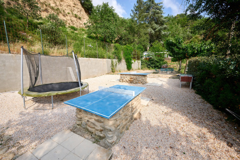 Buitenactiviteitenzone bij Camping Le Canigou met pingpongtafel, trampoline en tafelvoetbal.