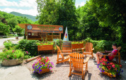 Outdoor seating with wooden chairs and flowers near Aventure Active at Camping Le Canigou, Occitanie, France.