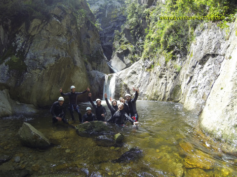 Gruppo di persone con caschi e mute in un fiume tra le rocce al Camping Le Canigou, Occitania, Francia.