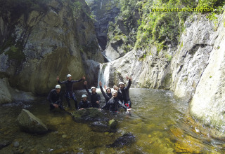 Gruppe von Leuten mit Helmen und Neoprenanzügen steht im Fluss bei Camping Le Canigou, Occitanie, Frankreich.