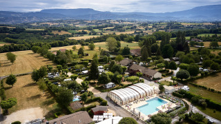 Vue aérienne du Camping Le Coin Tranquille en Auvergne-Rhône-Alpes, France, avec piscine et paysage verdoyant.