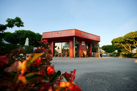 Reception building at Camping Le Coin Tranquille holiday park in Auvergne-Rhône-Alpes, France, with flowers.
