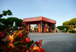 Reception building at Camping Le Coin Tranquille holiday park in Auvergne-Rhône-Alpes, France, with flowers.
