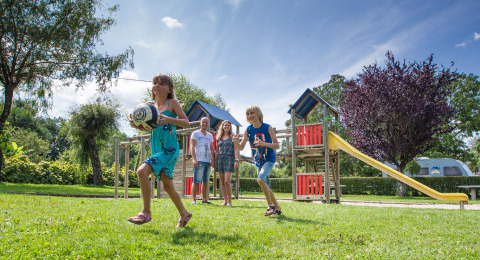 Niños juegan con una pelota en un área de juegos en Camping Le Coin Tranquille, Auvergne-Rhône-Alpes, Francia.