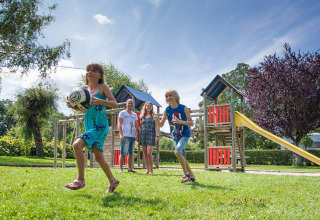 Kinder spielen mit einem Ball auf einem Spielplatz im Camping Le Coin Tranquille in Auvergne-Rhône-Alpes, Frankreich.