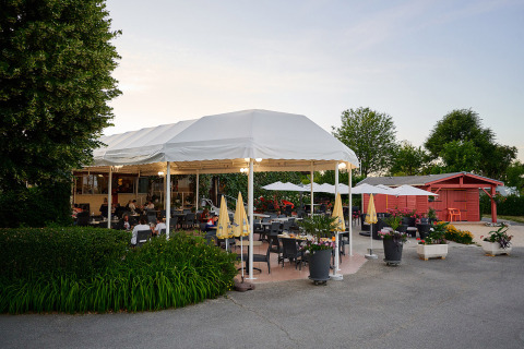 Zona de comedor al aire libre con toldos y sombrillas blancas en Camping Le Coin Tranquille, Francia.