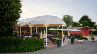 Zona de comedor al aire libre con toldos y sombrillas blancas en Camping Le Coin Tranquille, Francia.