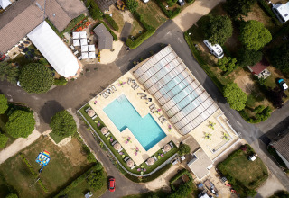 Luftfoto af Camping Le Coin Tranquille med swimmingpool, liggestole og grønne områder i Frankrig.