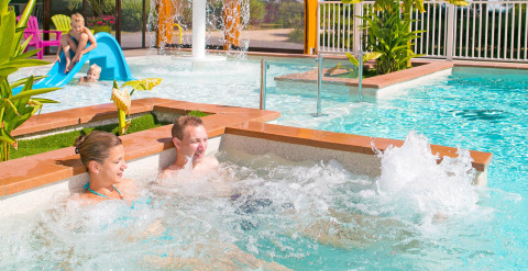 Familie nyder pools og børnevenlig rutsjebane på Camping Le Coin Tranquille i Auvergne-Rhône-Alpes, Frankrig.