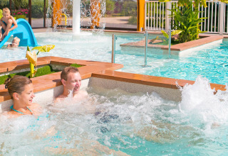 Familie nyder pools og børnevenlig rutsjebane på Camping Le Coin Tranquille i Auvergne-Rhône-Alpes, Frankrig.