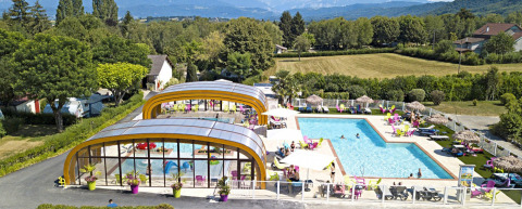 Camping Le Coin Tranquille in Auvergne-Rhône-Alpes con piscine interna ed esterna, lettini e vista sulle montagne.