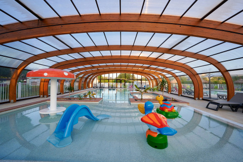 Piscina cubierta con toboganes y juegos infantiles en Camping Le Coin Tranquille, Auvergne-Rhône-Alpes, Francia.