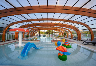 Indendørs swimmingpool med rutsjebaner og legetøj til børn på Camping Le Coin Tranquille i Auvergne-Rhône-Alpes.