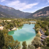 Scenic aerial view of Camping Le Lac Bleu in Auvergne-Rhône-Alpes, France with lake, cabins, and mountains.