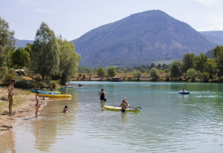 People relaxing and kayaking at the lakeside of Camping Le Lac Bleu, Auvergne-Rhône-Alpes, France.